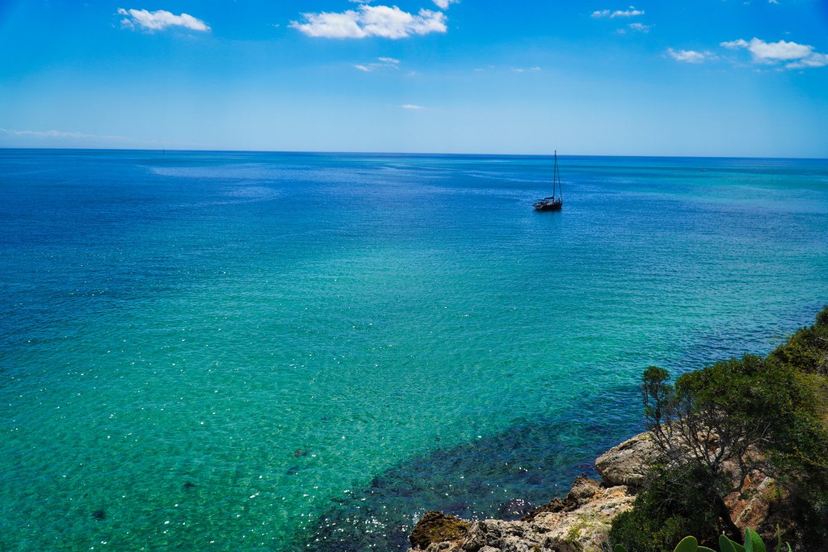 Calm turquoise water and a sailboat off the Portuguese coast